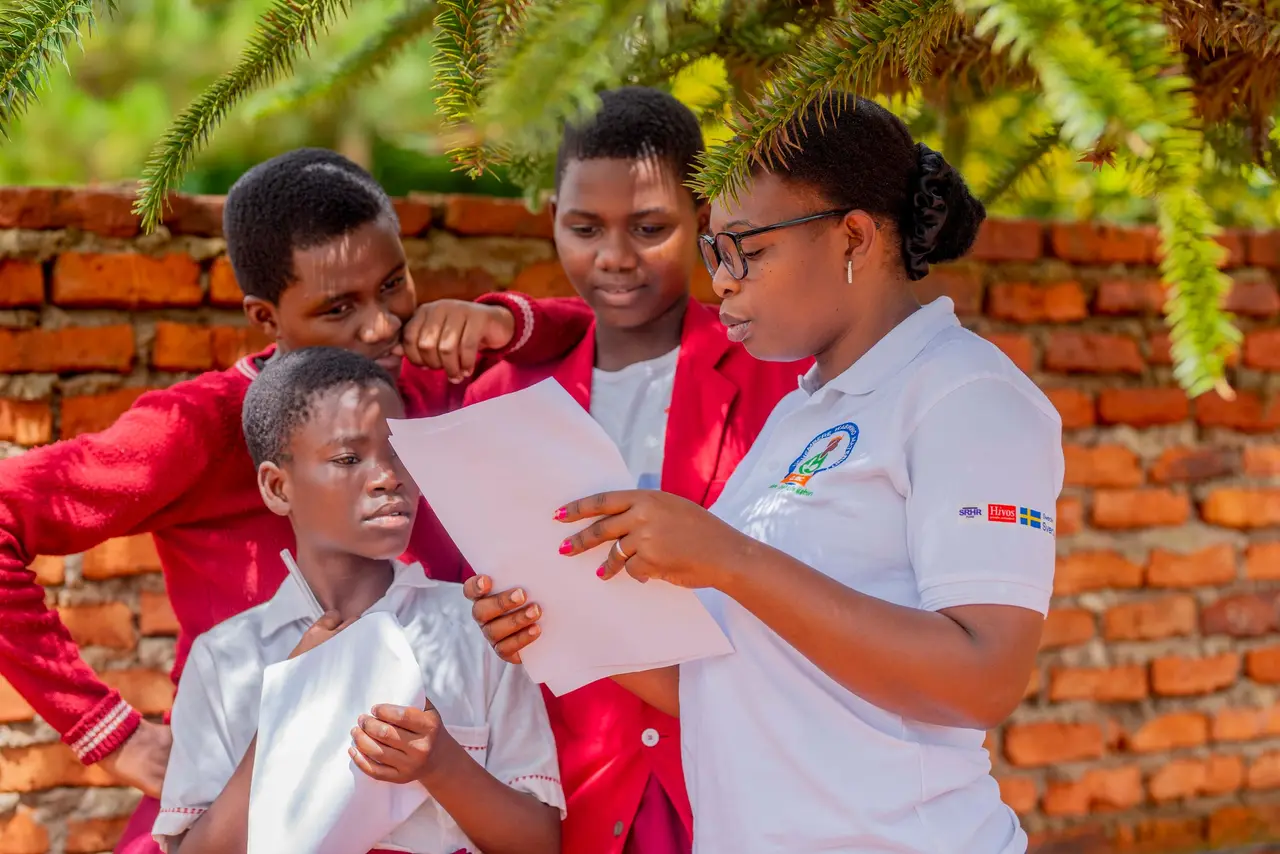 A facilitator going through a handout with three young learners outside