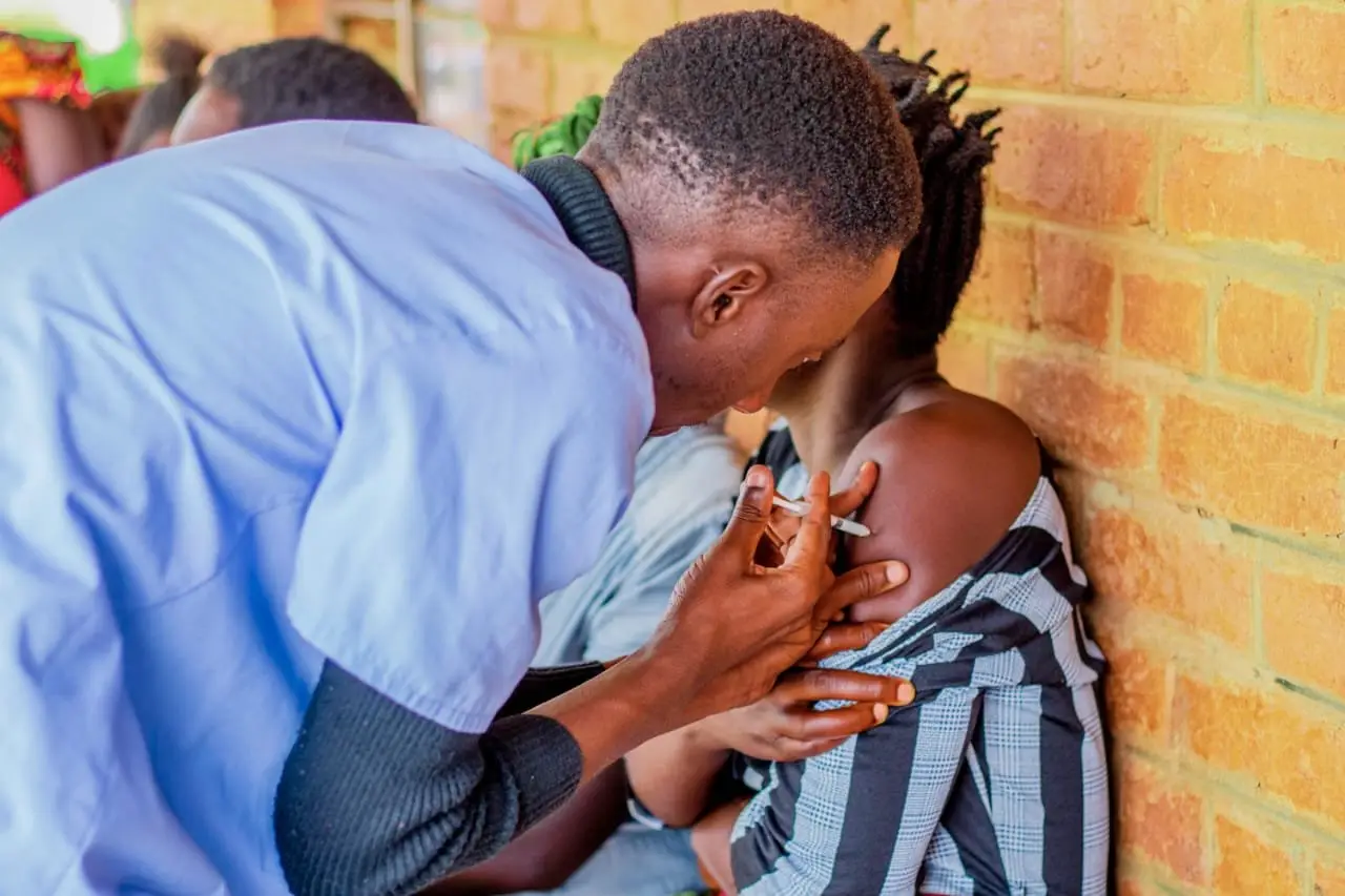 A health surveillance assistant giving a woman the tetanus toxoid vaccine during outreach