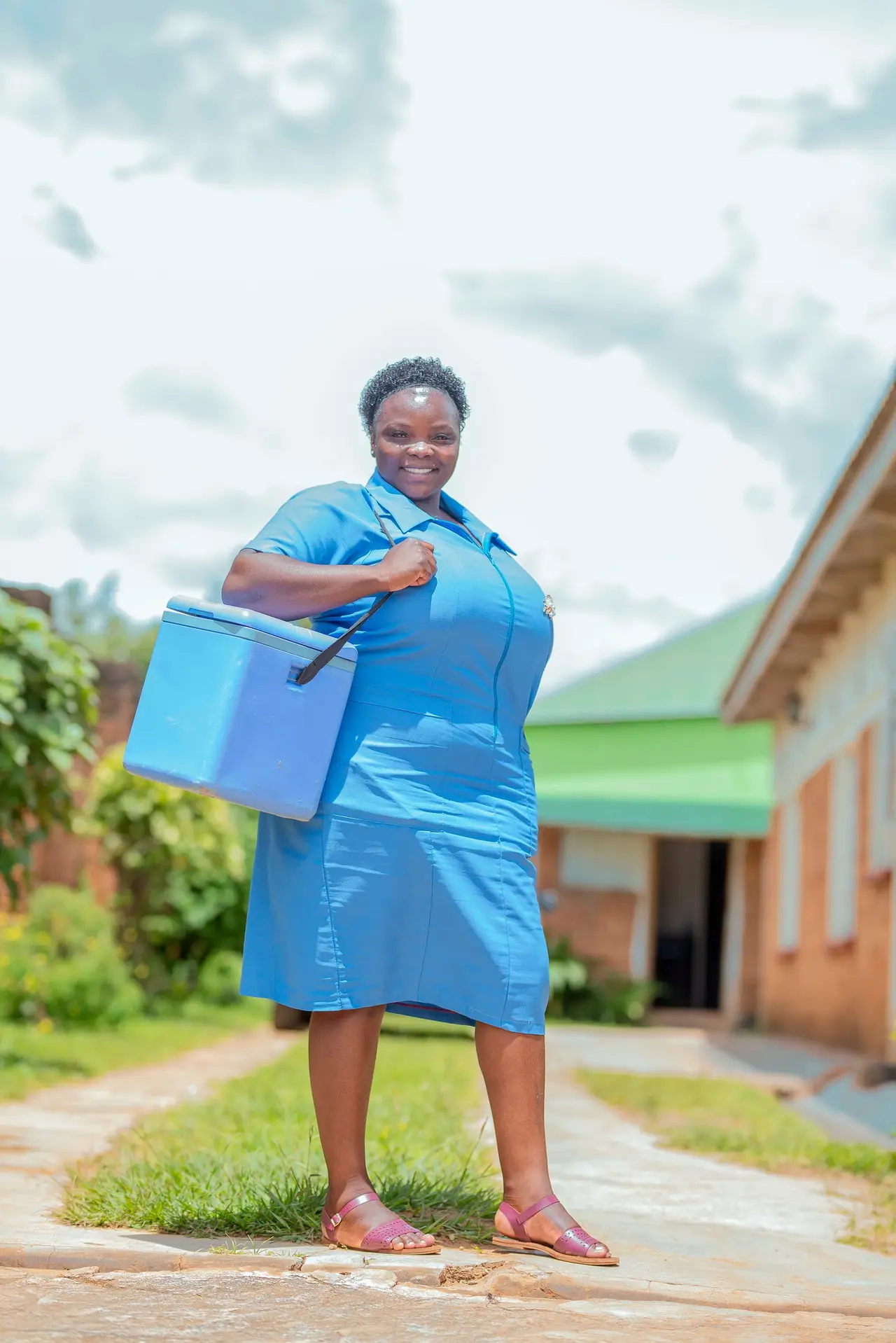 A health surveillance assistant setting out with a vaccine cool box