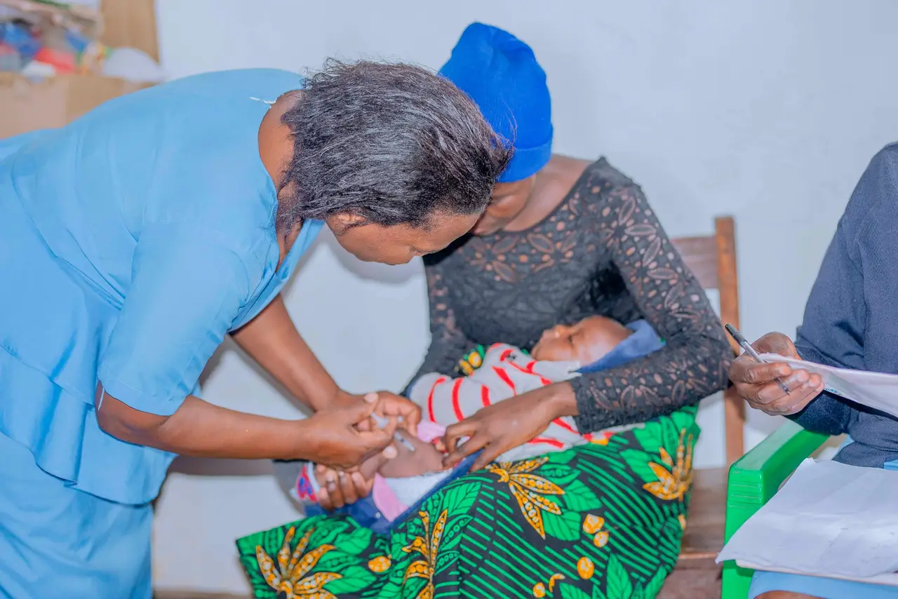 A nurse attending to a baby on the mother’s lap at an outreach clinic