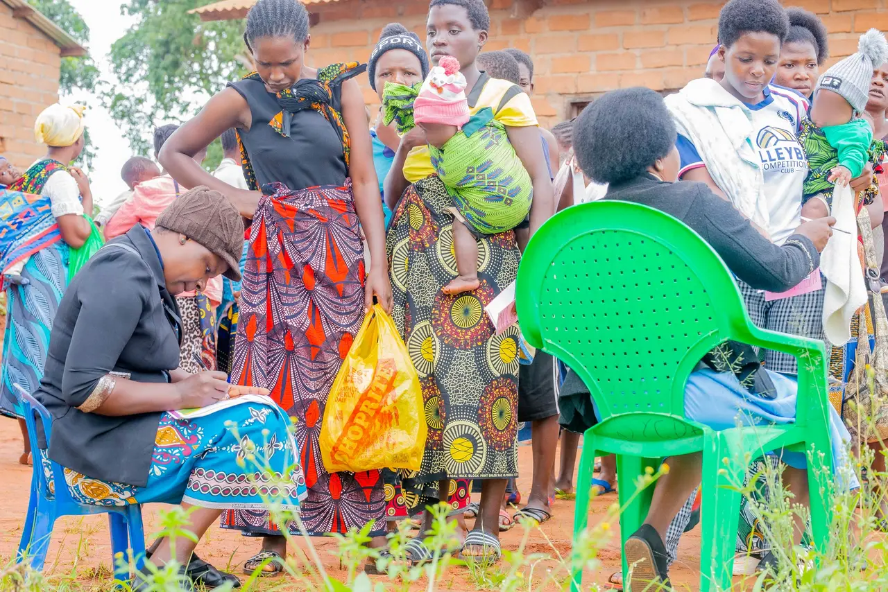 Mothers with babies waiting their turn as a health worker records details at an outreach clinic
