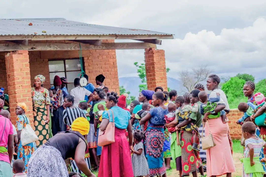 Women and children gathered outside a rural health post for an outreach clinic