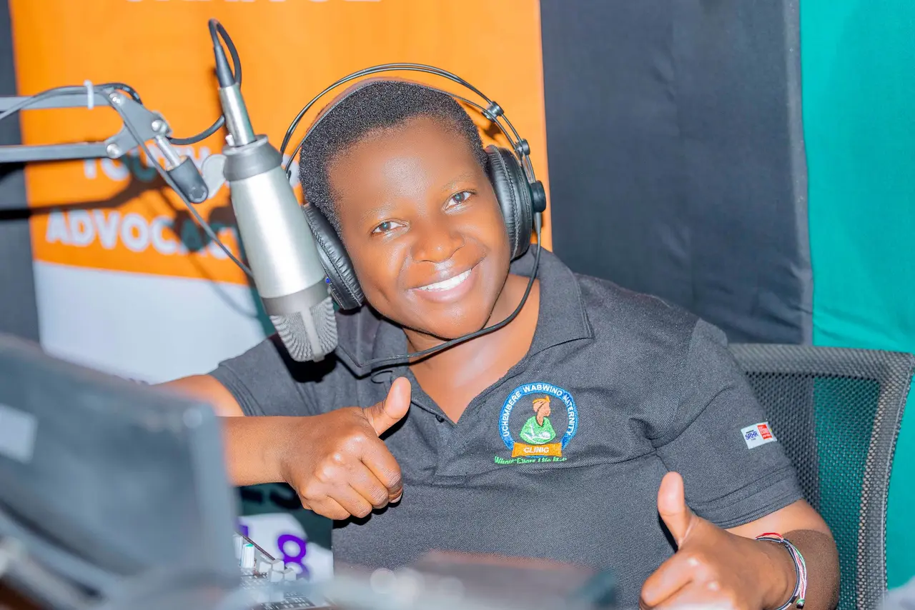 A member of the Uchembere Wabwino team giving a thumbs-up in a radio studio during an SRHR programme