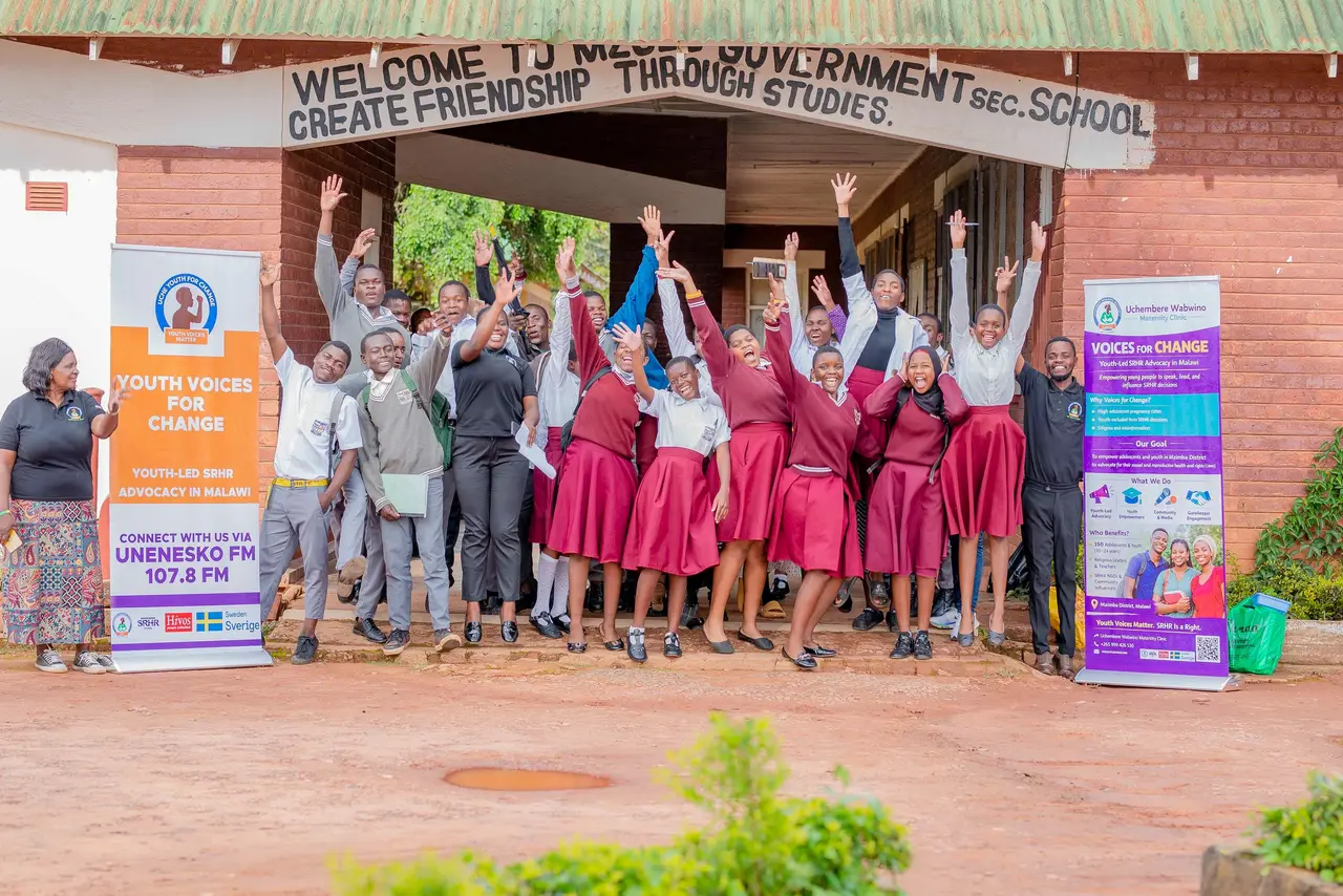 Learners cheering with the Voices for Change team and banners outside a secondary school